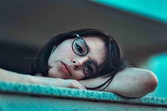 photo of woman in eyeglasses resting her head on arm